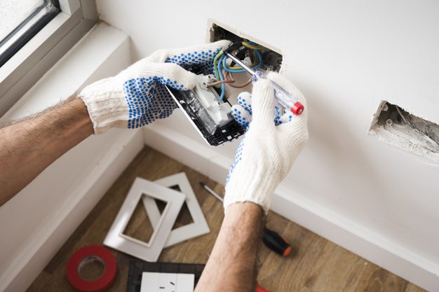 Electrician installing power socket at home